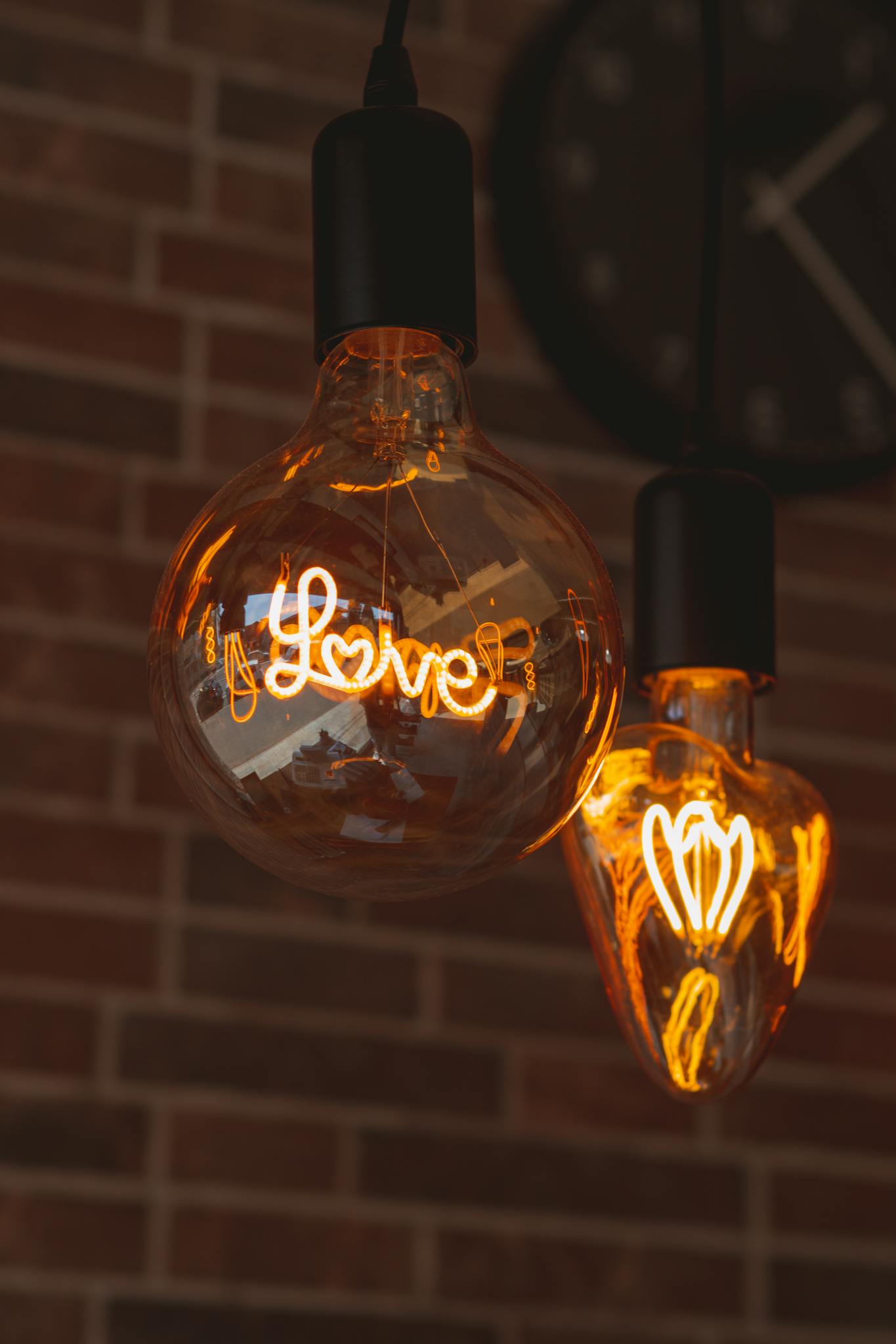 Warm glowing light bulbs with 'love' text against a brick wall, creating a cozy indoor atmosphere.