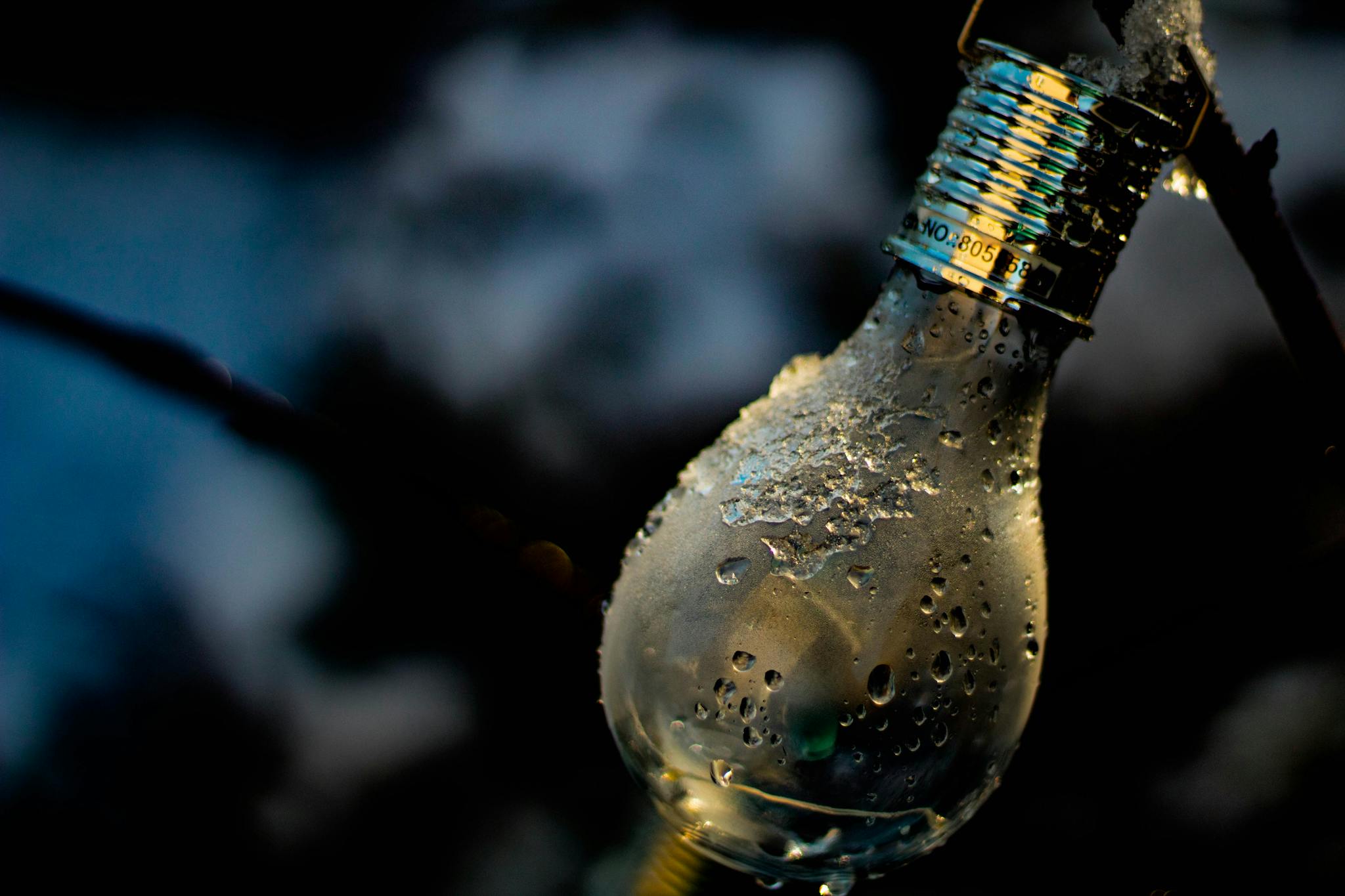 Detailed shot of a light bulb covered in water droplets and ice.